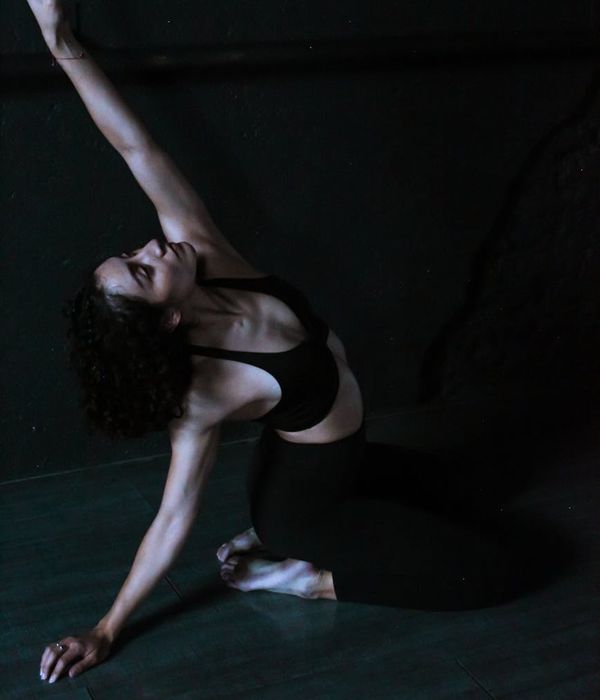 Woman in a graceful morning yoga pose against a calm, dark background.